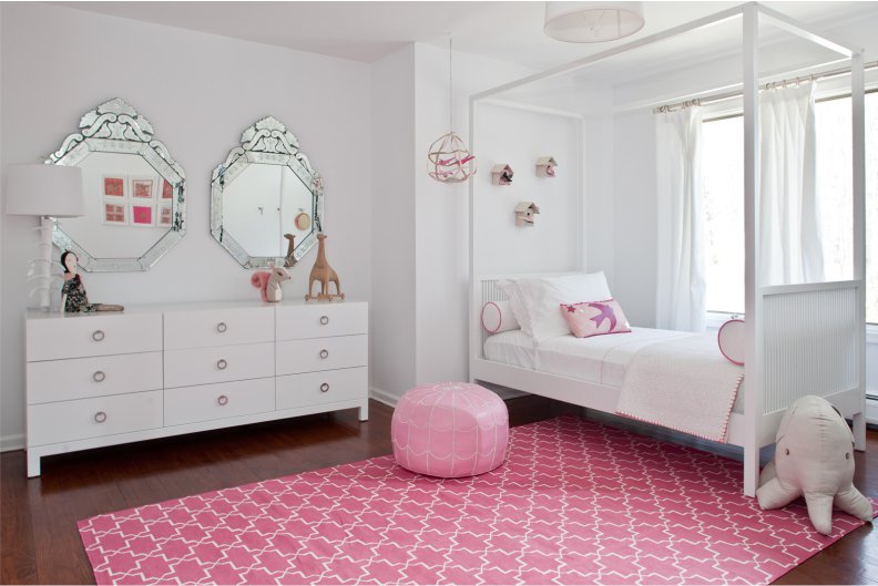 Розовый ковер в интерьере белой детской комнаты девочки