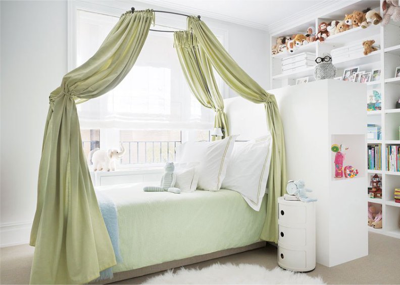 Зеленый балдахин в интерьере белой детской спальни